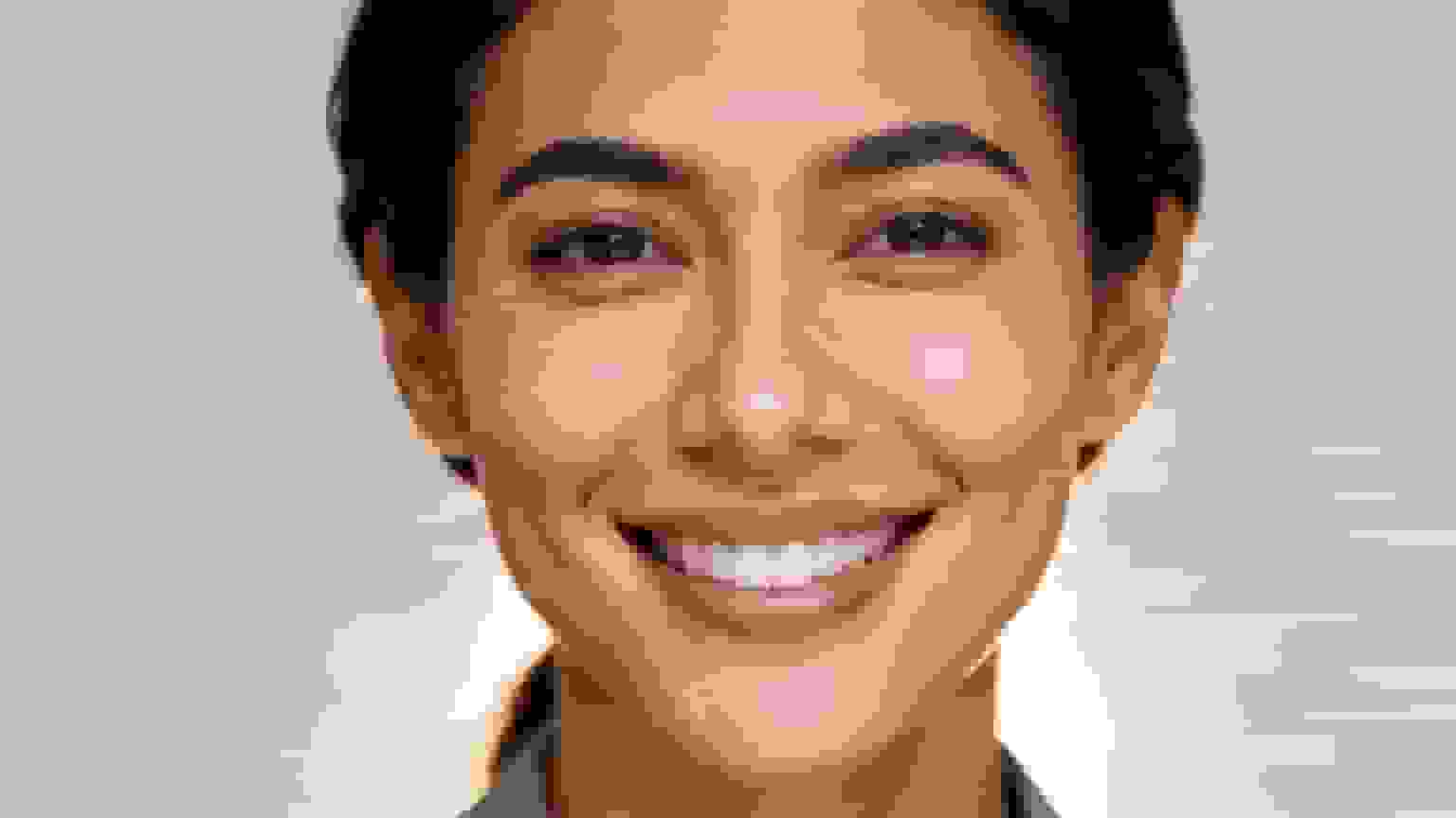 A professional headshot of a smiling woman with clear skin and bright eyes.