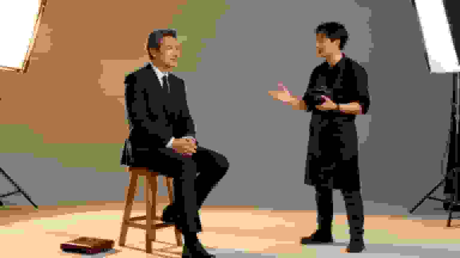 A professional photographer consults an executive in a studio for a corporate headshot session.