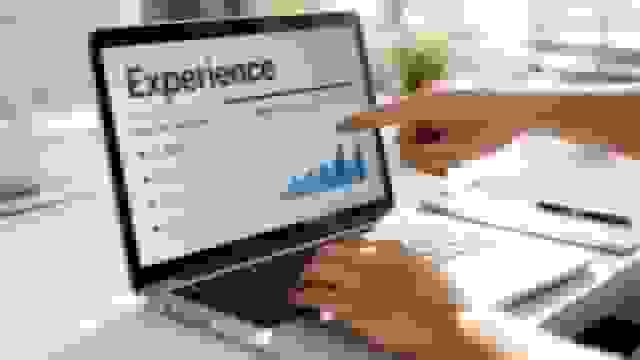 Person's hands on a laptop, pointing at a business graph displaying 'Experience' and 'Measural results'.