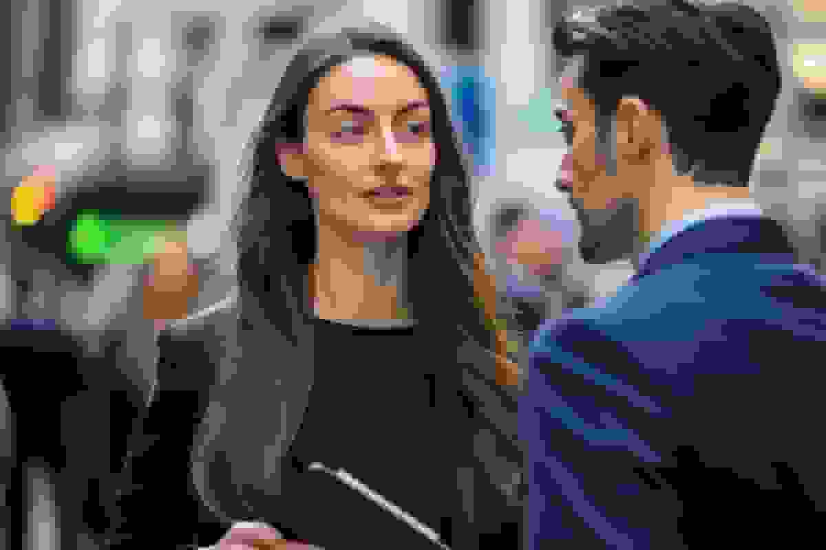 Two people in business dress talking on a busy city street