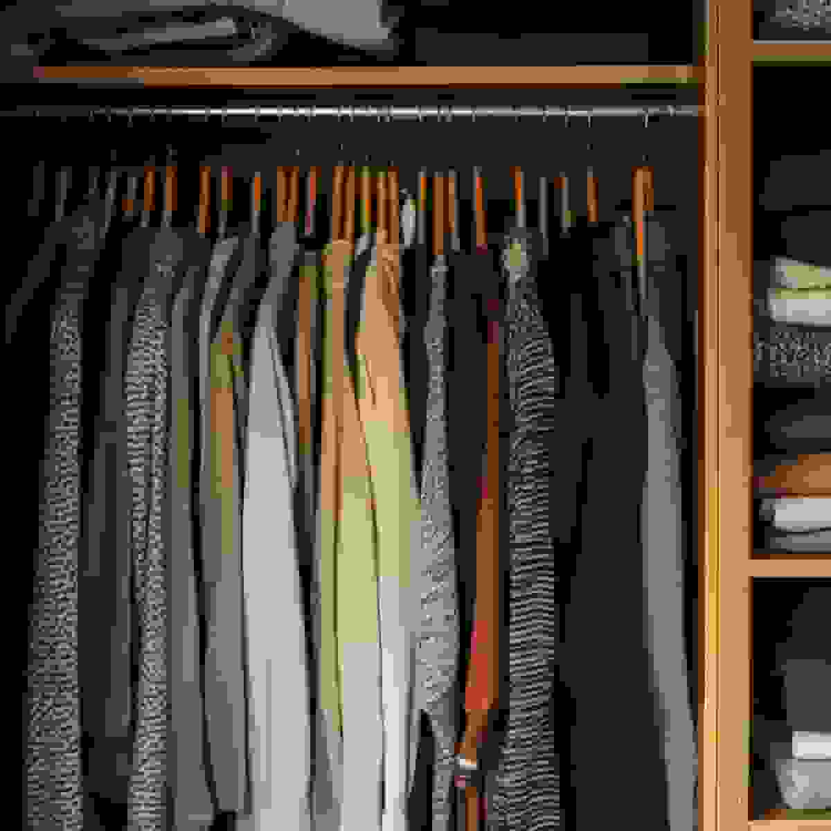 A wardrobe rail hung with neutral knitwear and jackets in muted tones