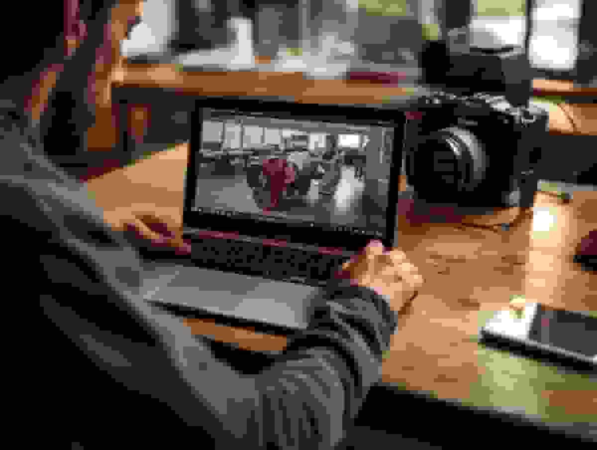 A photographer reviewing images on a laptop beside a DSLR camera