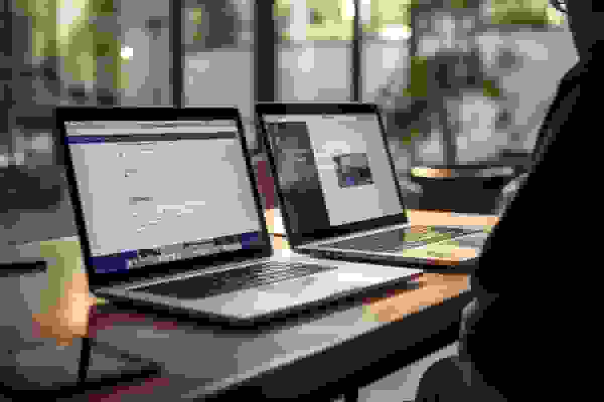 Two laptops open side by side on a desk in a modern office