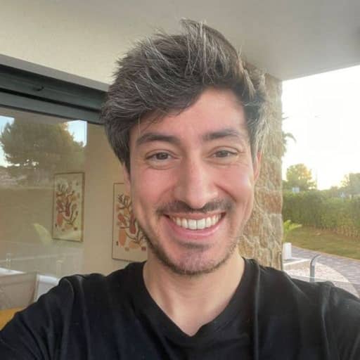 Input photo 1: selfie of a man with thick greying hair and a beard in a black t-shirt, smiling in a bright living room