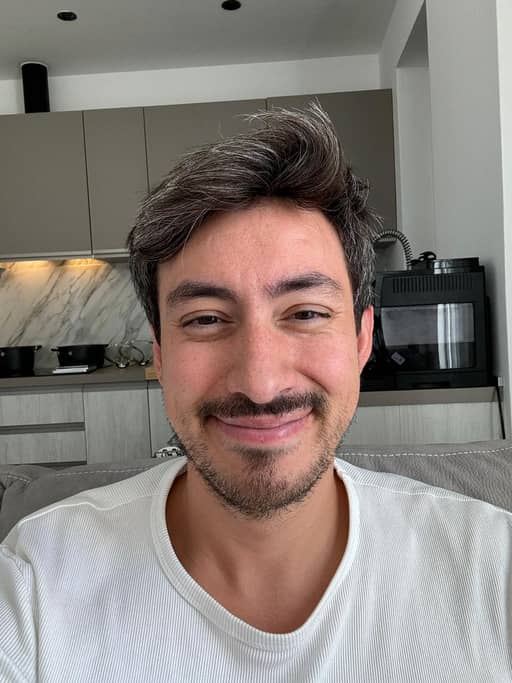 Input photo 7: selfie in the same kitchen in a white t-shirt, closed-mouth expression