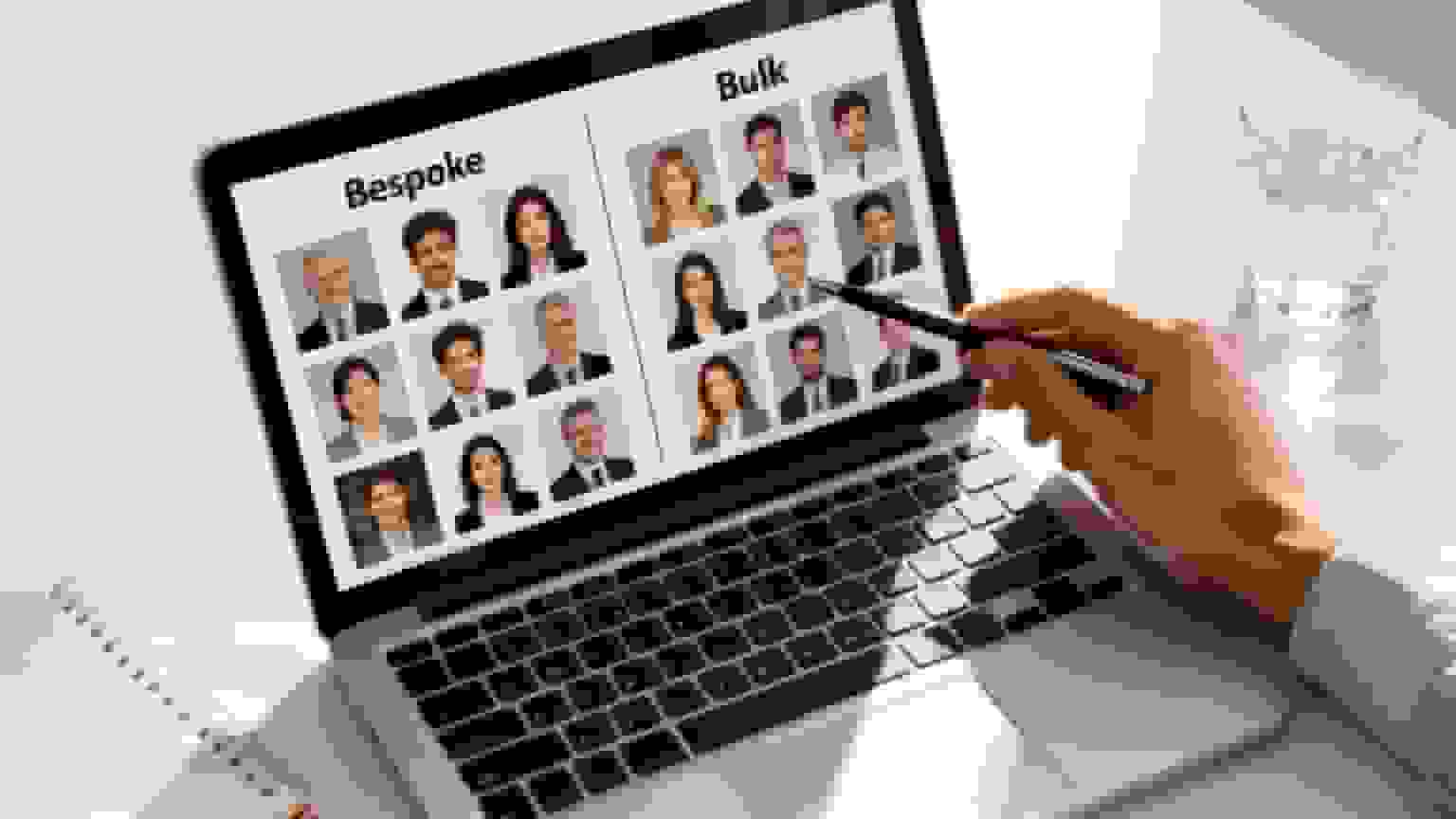 Hand pointing at laptop screen showing bespoke and bulk corporate headshots, illustrating professional photography services.